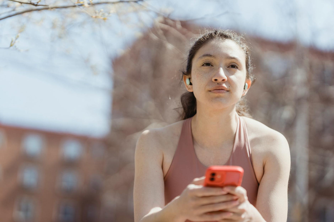 Persoană cu AirPods în urechi, ascultând muzică în mișcare pe fundal urban